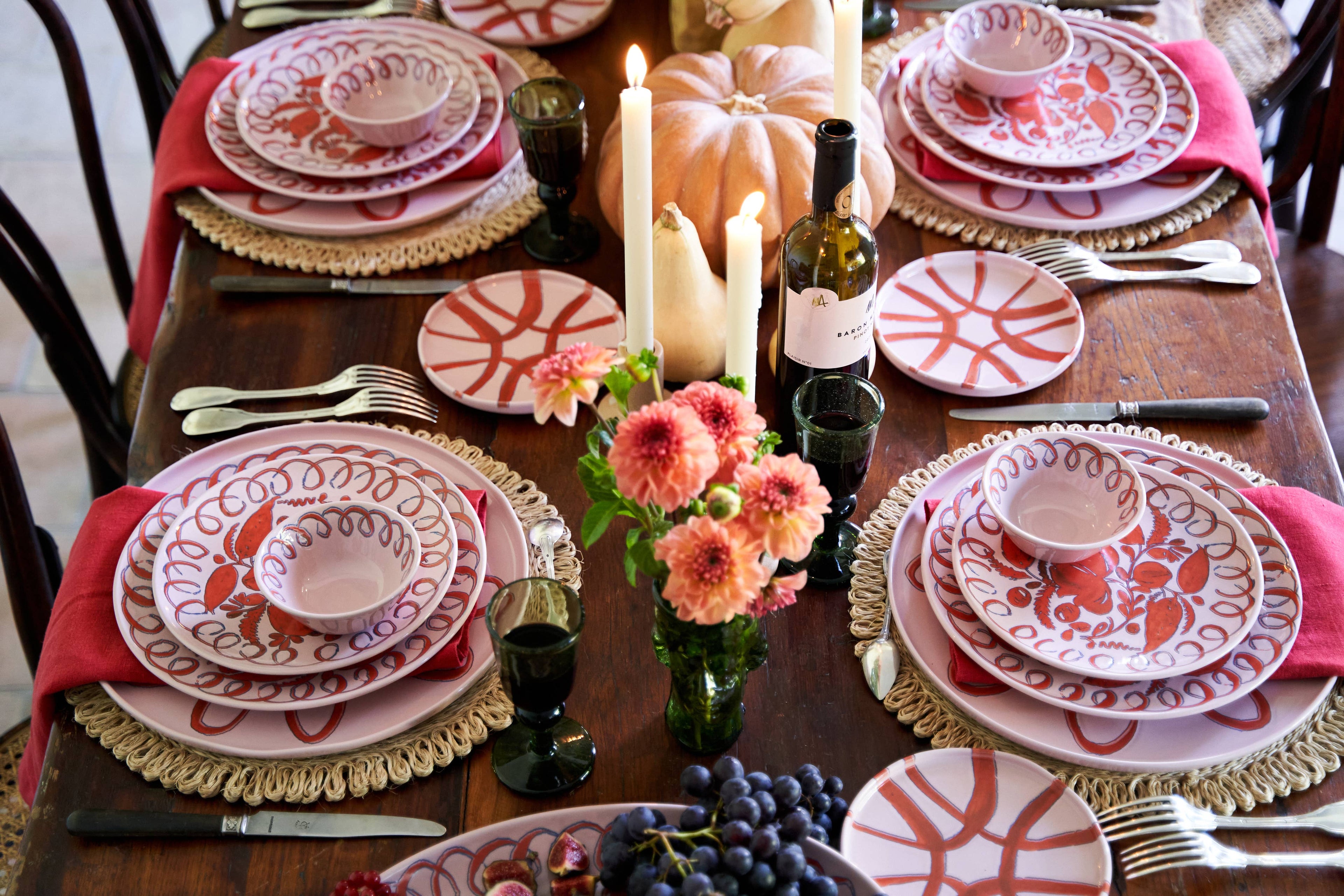 Decorative table setting with patterned plates, candles, and flowers on a wooden table.