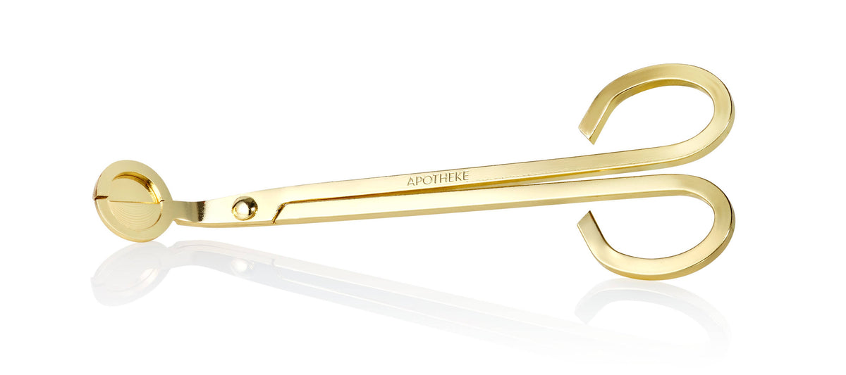 Gold-colored candle wick trimmer on a white background