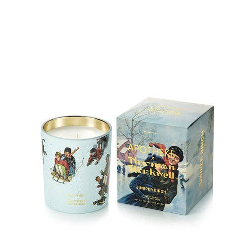A light blue scented candle with a gold-rimmed glass vessel and winter-themed illustrations, shown next to its matching illustrated packaging box on a white background.