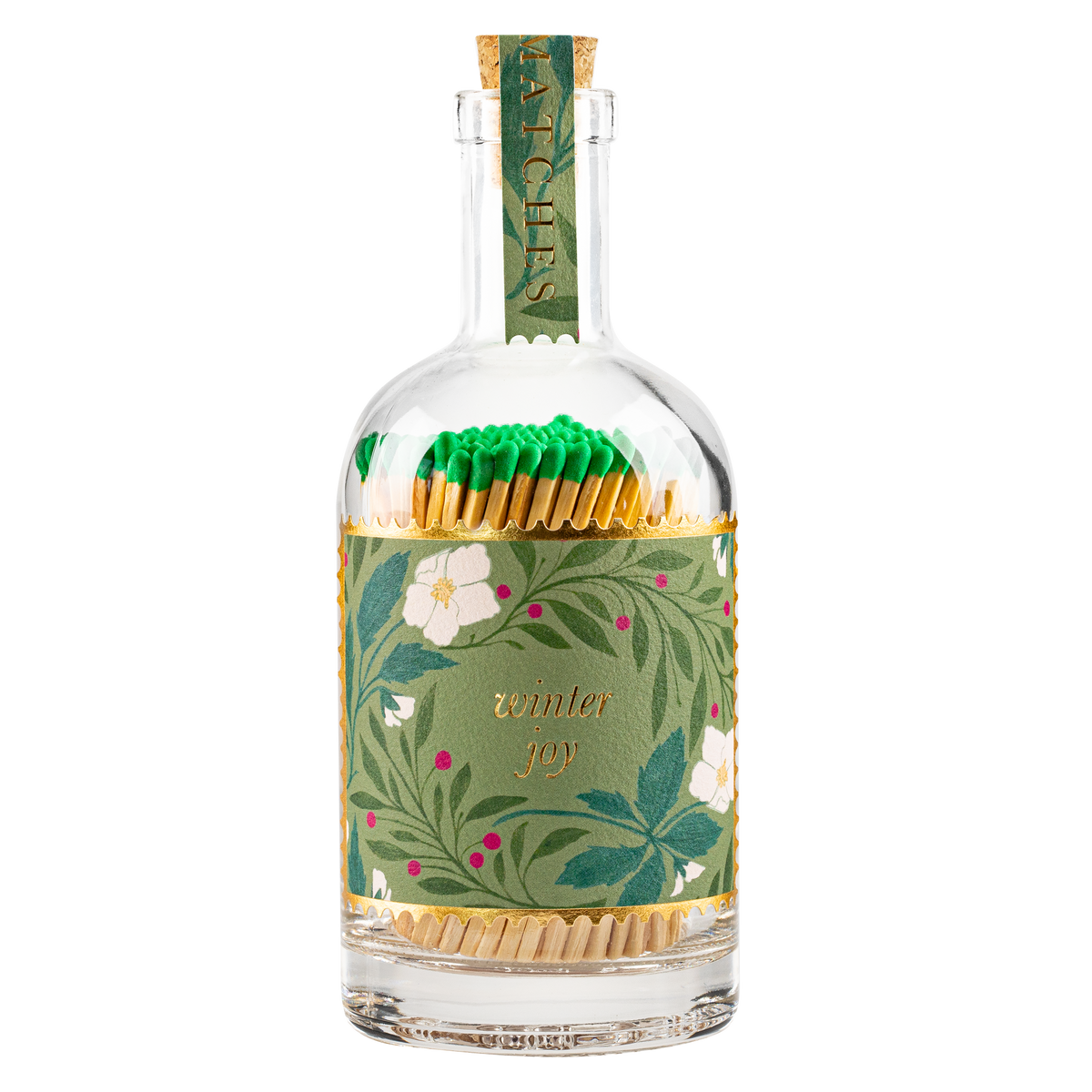 An Archivist clear glass bottle filled with wooden matchsticks, wrapped in a green botanical paper sleeve with white flowers and gold lettering that reads 'winter joy.' The bottle is topped with a matching green paper neck wrap.