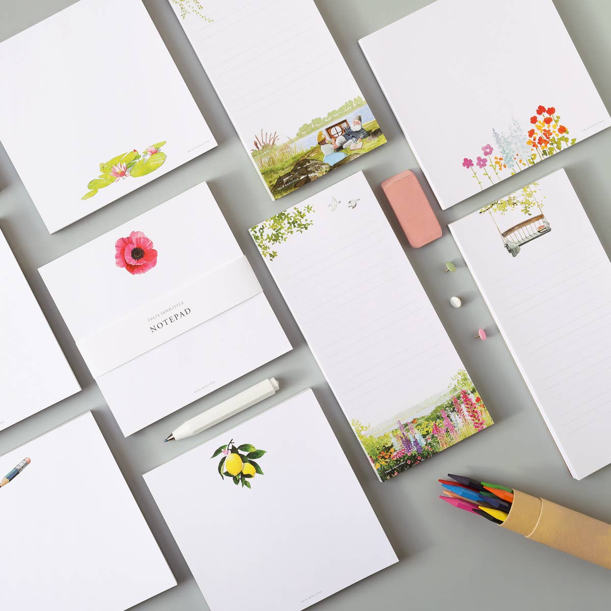Collection of Felix Doolittle stationery items including notepads and a pink eraser on a gray surface.