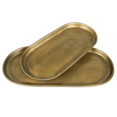 A set of two oval brass trays stacked on a white background