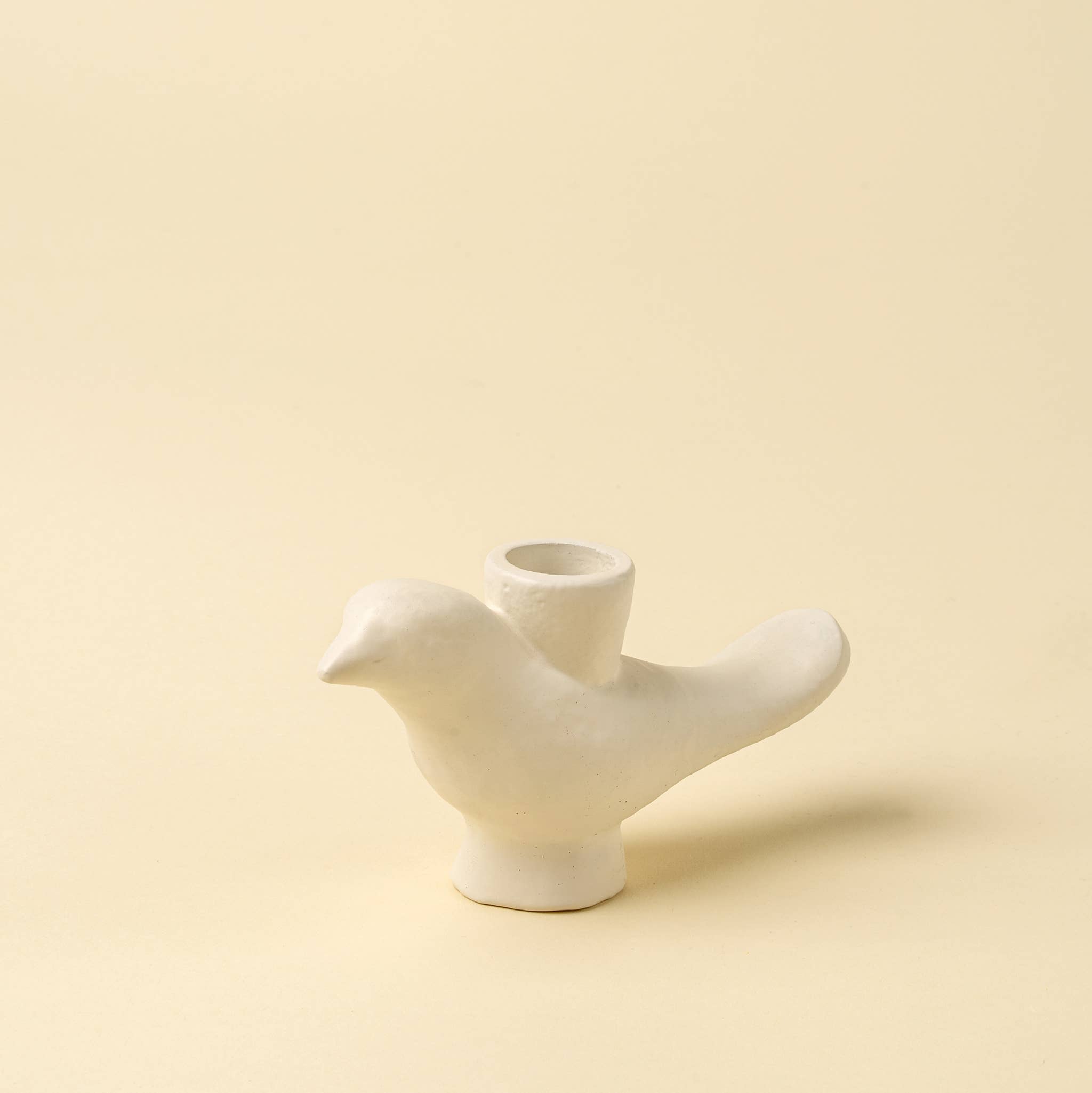 White ceramic bird-shaped vase on a beige background