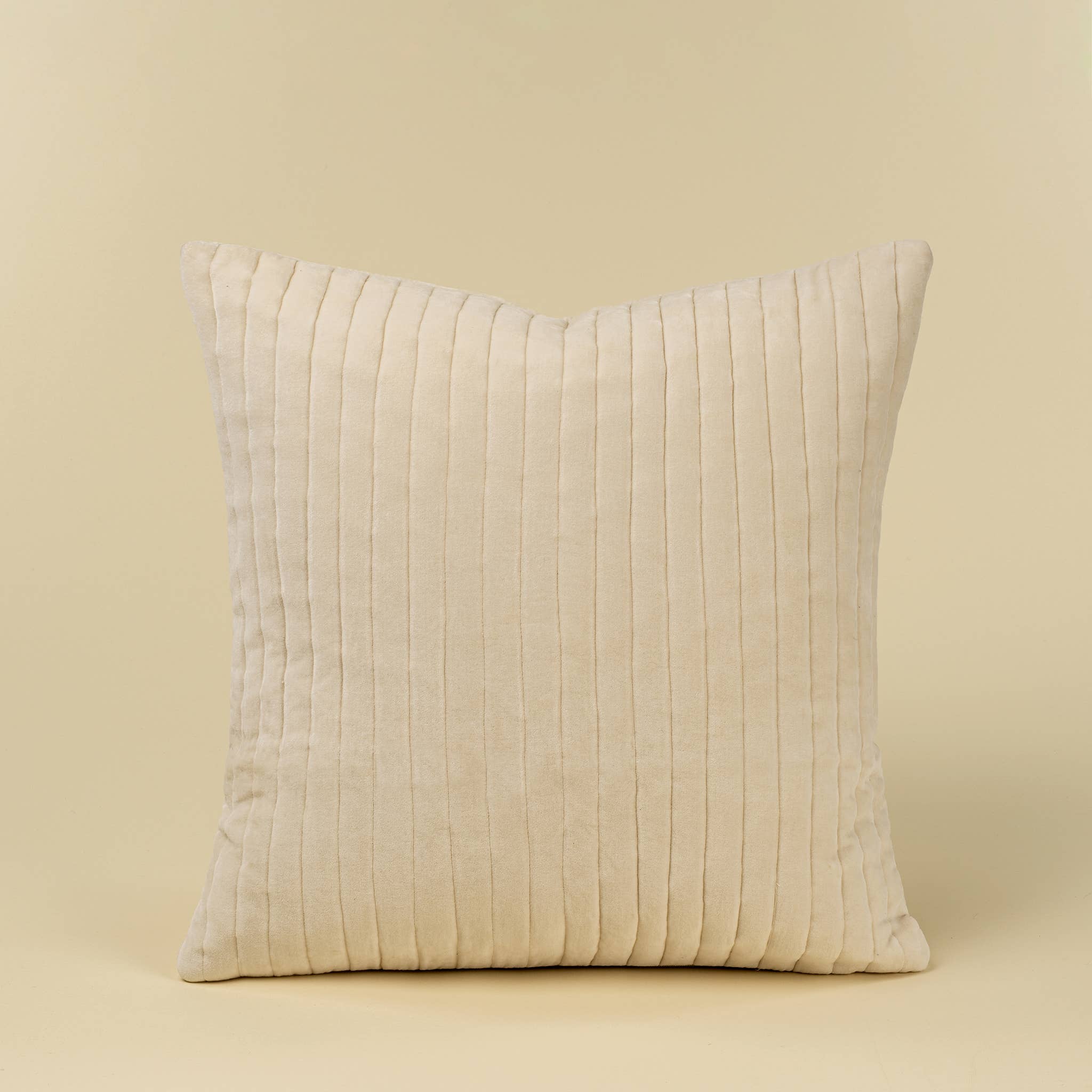 A square throw pillow in an ivory velvet fabric with vertical pleats, shown against a solid beige background.