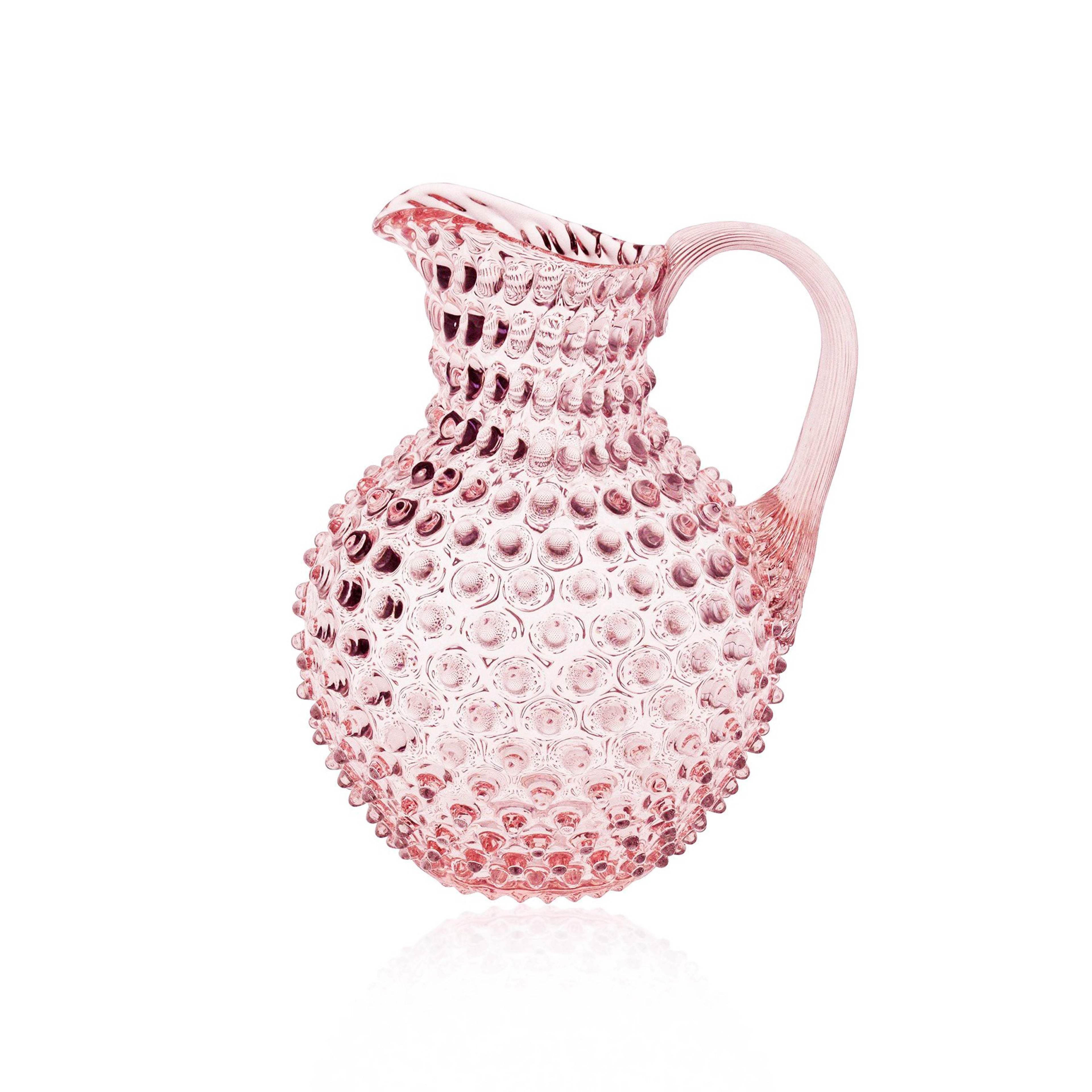 Pink Klimchi hobnail glass pitcher with textured surface on a white background