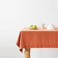 Baked clay linen tablecloth on a wooden table set with white dishes and pears