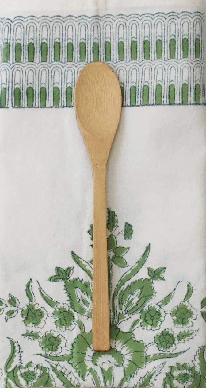 Wooden spoon on a green and white block print patterned cotton napkin background