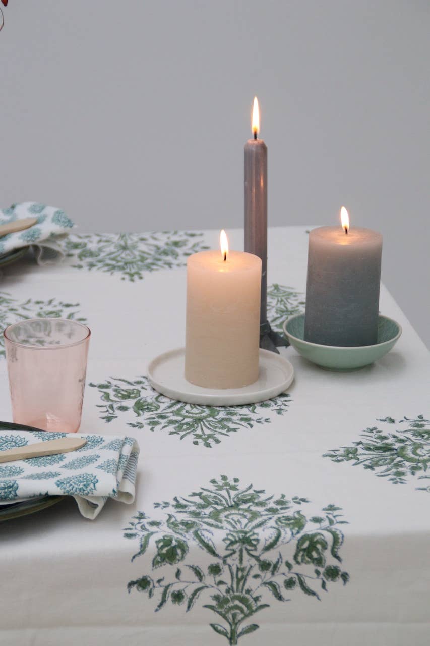 Candles on a table with a green, blue & white block print tablecloth