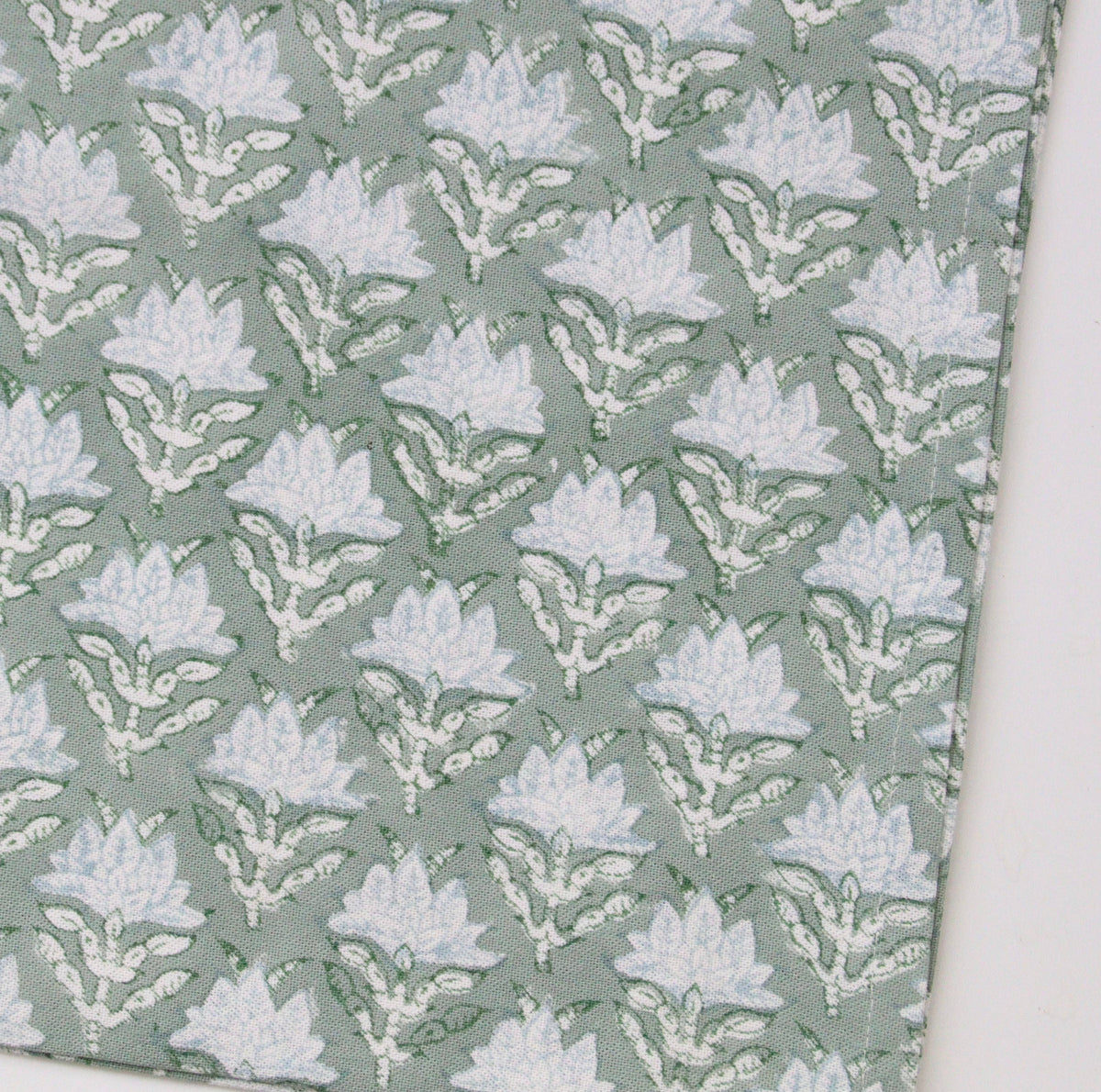 Block print patterned tea towel or dish towel with white floral design on a green background