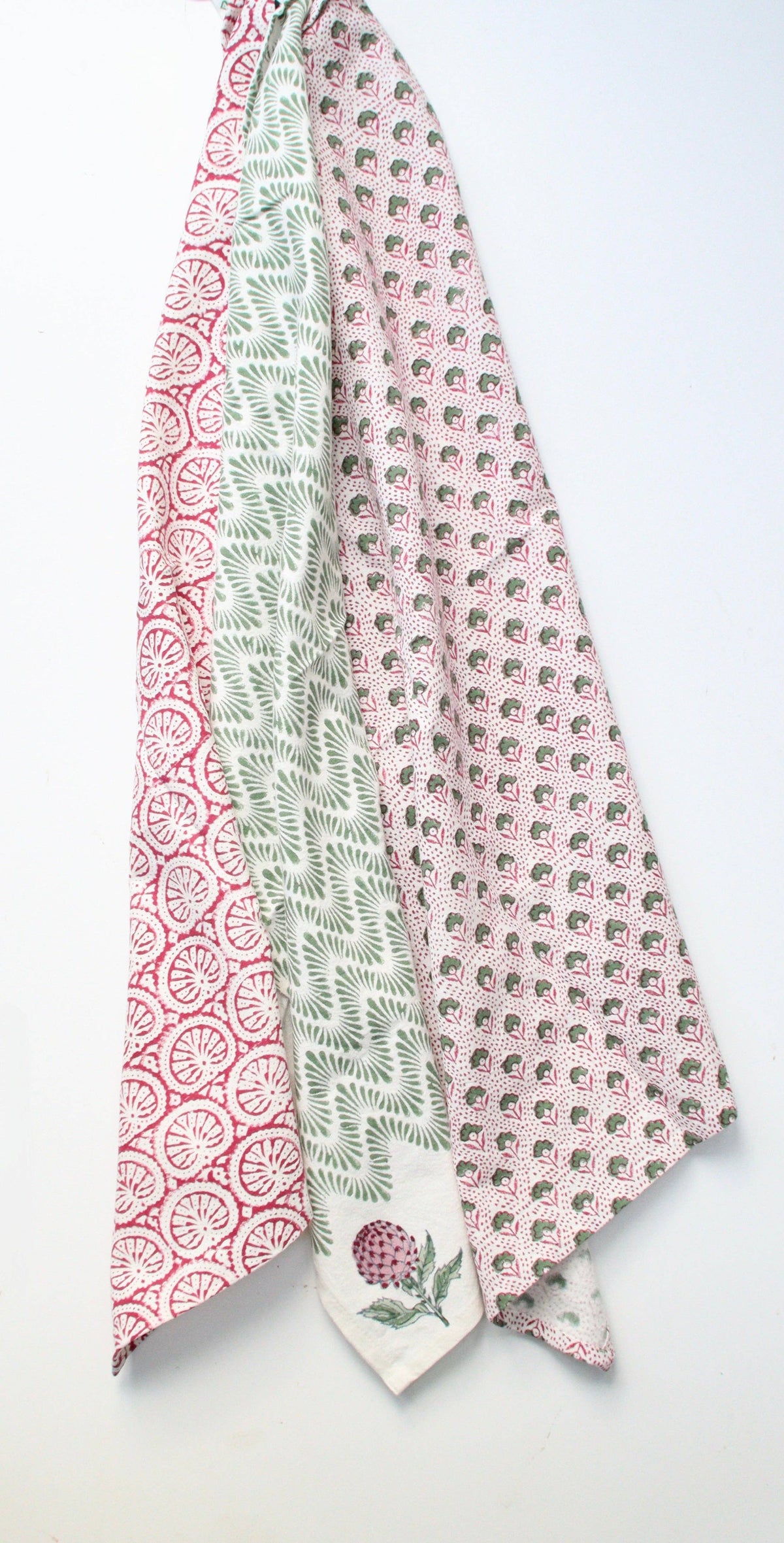 Three colorful block print patterned tea towels or dish towels on a light gray background