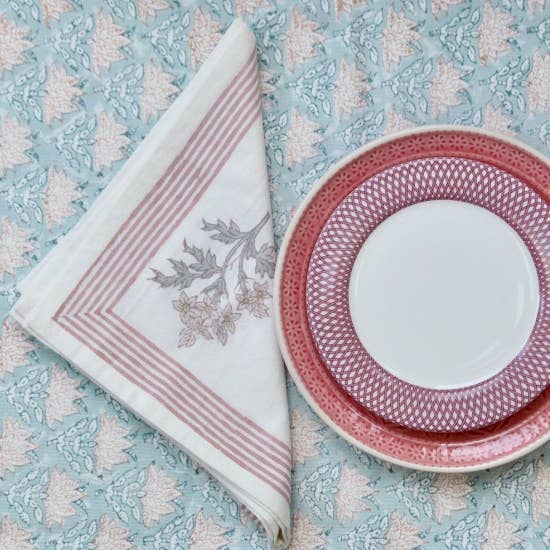 Cotton Napkin with pink and green floral block print design and plate with pink rim on patterned tablecloth
