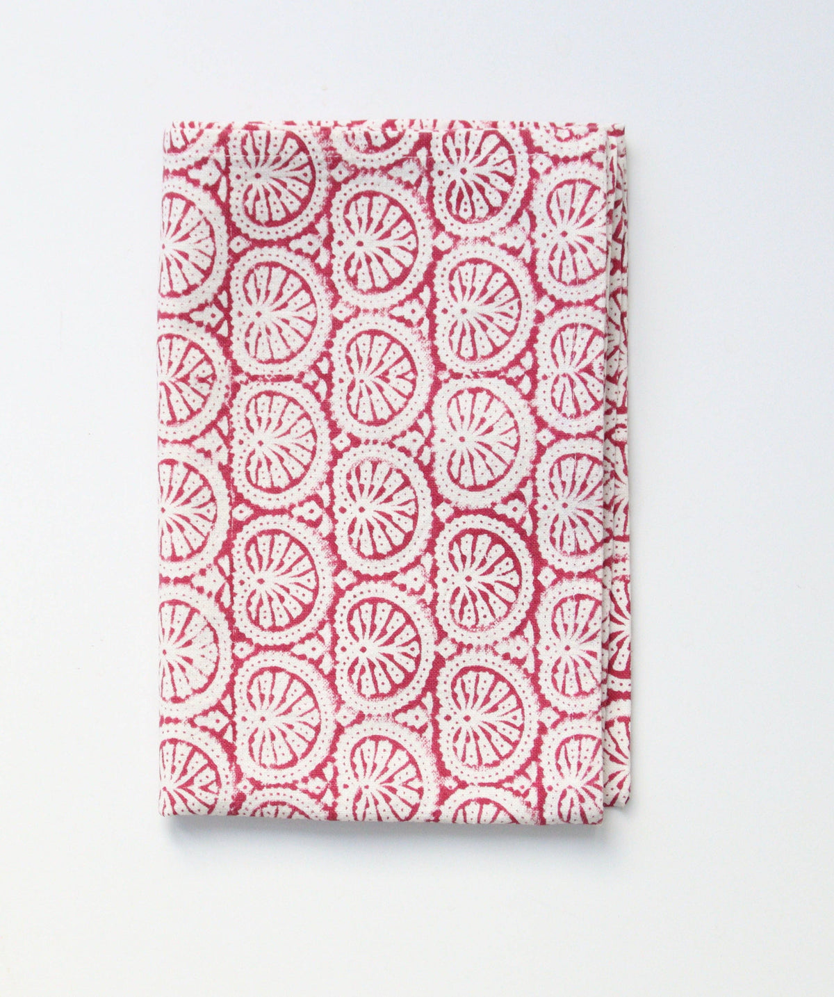 Folded tea towel or dish towel with pink and white block print pattern on a light gray background