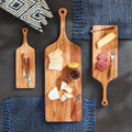 Three wooden cutting boards with various food items on a dark surface with blue textured mats.