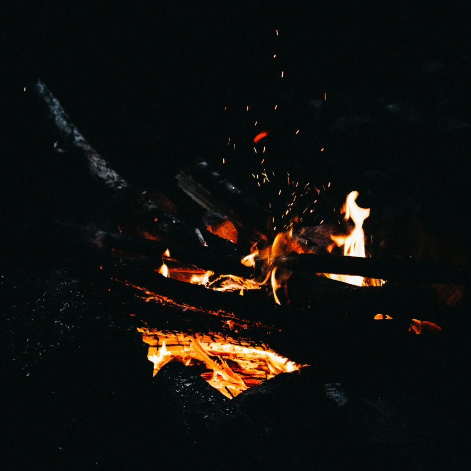 Fire burning in a dark setting with flames and embers visible St Eval
