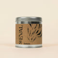 A cylindrical metal tin scented candle with a silver lid and base, wrapped in a brown kraft paper label with black text reading 'StEVAL' and 'Embers', set against a solid light beige background.