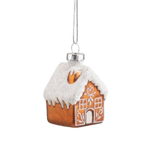 A gingerbread house Christmas ornament with white icing details and a silver hanging loop, shown against a plain white background.